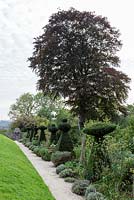 Topiary chesspieces along a path. Hanham Court Gardens, Bristol.