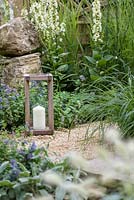 A candle on a gravel bed with Pennisetum villosum and Nepeta x fassenii- The Drought Garden, RHS Hampton Court Palace Flower Show 2016.