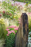 Smoldering Wood beam surrounded by Purple Coreopsis, Achillea 'Summer Fruits Lemon', Achillea 'Summer Fruits Carmine', echinaceas and Stipa tenuissima. Great Gardens of the USA: The Austin Garden, RHS Hampton Court Flower Show in 2016. Designer: Sadie May Stowell - Sponsor: Brand USA