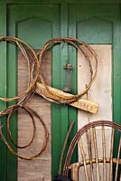 Woven willow plant supports hanging on green painted shed - June
