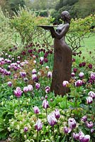 Sculpture 'Clemmie' by Alexandra Beale underplanted with Tulipa 'Rem's Favourite', Tulipa 'Curly Sue' and Hellebores, in the Stellata beds