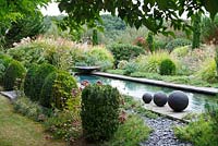 Three stoneware balls are placed by the side of the pool of the Contemporary Garden, Les Jardins de la Poterie Hillen