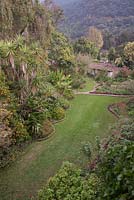 Aerial view of gardens with borders, terracotta roofed house and tree covered hills beyond - Lake Atitlan Hotel, Guatemala
