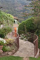 Stone path up curving slope with rusty coloured iron railings in tropical gardens with views to tree covered hills - Lake Atitlan Hotel, Guatemala