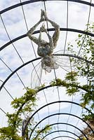 A fairy created with galvanised and stainless steel wire by artist Robin Wight, hangs in the Trellis Walk at Trentham Gardens, Staffordshire