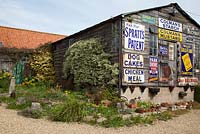 An old barn decorated with vintage advertising signs at Cliff and Joan Curtis's garden, Chapel Street Bourne, Lincolnshire