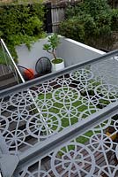 Overhead view of grey metal laser cut pergola roof showing the deck and seating area below.