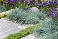 Stone globe and grey stone slabs surrounded by Festuca glauca, Lavandula angustifolia and  Thyme. Living Landscapes: Healing Urban Garden, RHS Hampton Court Palace Flower Show 2015. Designer Rae Wilkinson