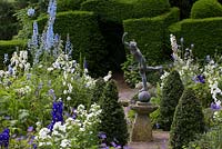 Blue and white formal garden with delphiniums and phlox around Mercury statue