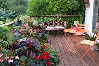 Decorative bright orange garden furniture on decked terrace with colourful summer containers. Patio garden. Owner: Pattie Barron