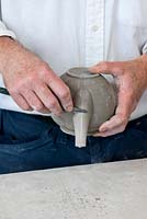 Stephen cleans off the seam created along the teapot's sides where the mould split open. This process is known as 'fettling'.