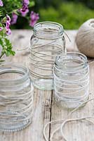 Making garden lanterns. Wrap jam jars in string