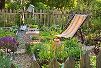 Deckchair in mixed borders of vegetables and herbs. 