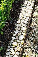 Stones set into a salvaged steel girder form a border edging.