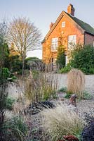 Gravel garden in front of the house includes small trailing conifer Larix decidua 'Puli', Ophiopogon planiscapus 'Nigrescens' and grasses. 'Windy Ridge, Little Wenlock, Shropshire, UK