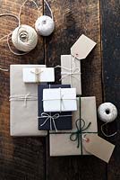 Lots of presents wrapped with brown and white paper and fastened with string, with gift tags and string.