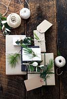 Lots of presents wrapped with brown and white paper and fastened with string, with gift tags and string.  Decorated with fir tree, yew tree and silvery foliage