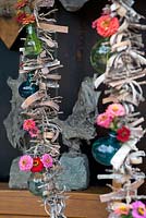 Garland made of bark with Zinnias in a small glass bottle