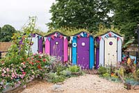 Colourful beach huts with wildflower green roofs, boat planted with Petunias and Runner Beans growing on a sail frame - Fun on Sea, RHS Hampton Court Palace Flower Show 2017