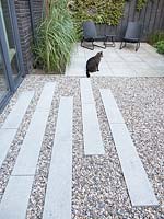 Gravel terrace with concrete tiles and pet cat