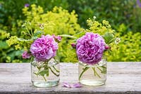 Pink roses in glass jar with fragaria vesca and alchemilla mollis