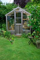 Garden view with wooden greenhouse and vegetable bed