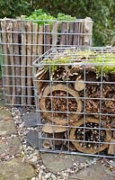 Insect hotel made from natural materials inside gabion container