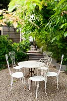 Metal seats and table on gravel terrace. Villa Singer Garden. Milan. Italy