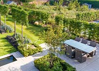 Long herbaceous borders lead to a patio area with a rill and seating, designed by Louise Harrison-Holland. Plants include Amelanchier lamarckii, box hedging, pleached Pyrus calleryana 'Chanticleer', Japanese anemones, Stachys, Persicaria, Ophiopogon planiscapus 'Nigrescens', and Miscanthus sinensis 'Kleine Fontaine'

