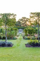 Lawns provide pathways leading to a summer house in a modern Cheshire country garden. It was designed by Louise Harrison-Holland. Planting includes pleached Pyrus calleryana 'Chanticleer', Japanese anemones, Miscanthus sinensis 'Kleine Fontaine', Anthemis, Phlox and Stachys.