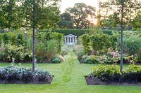 Lawns provide pathways leading to a summer house in a modern Cheshire country garden designed by Louise Harrison-Holland. Planting includes pleached Pyrus calleryana 'Chanticleer', Japanese anemones, Miscanthus sinensis 'Kleine Fontaine', Anthemis, Phlox and Stachys.