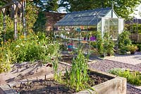 A greenhouse and raised beds for fruit, vegetables and cut flowers in a modern Cheshire country garden. It was designed by Louise Harrison-Holland.