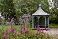 An aqua painted gazebo with trees behind and Astilbe chinensis var. taquetii 'Purpurlanze' in front