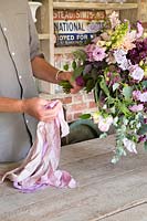 Man attaching silk ribbons to bouquet