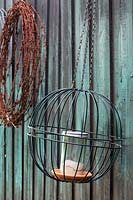 Two wire hanging basket frame attached to each other to make a sphere holding a candle in a glass container.