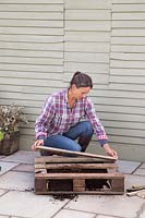 Woman placing wooden planks to create a back to the pallet