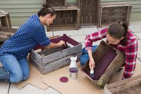 Woman and young girl painting inside of wooden crates