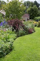 Curved lawn with tiered herbaceous border in June