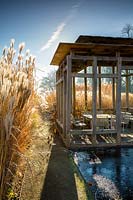 Modern summerhouse and seating area amongst grasses in winter, Bury Court Gardens, Hampshire. Designed by Christopher Bradley-Hole.