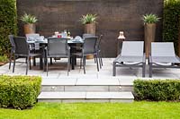 Dining furniture and sun loungers on contemporary patio in subrban garden