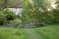 Path through wildflower meadow to stone steps in spring. Great Dixter, Sussex