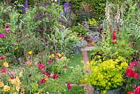 The Anneka Rice Colour Cutting Garden - Brick path leading between cut flower beds with Cosmos, Cirsium rivulare, Lupinus, Digitalis and Papaver.  Bucket filled with Smyrnium perfoliatum - BBC Radio 2 Feel Good Gardens - RHS Chelsea Flower Show 2017