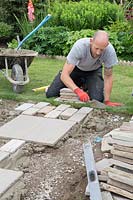 Man adding mortar as base for pavers laid in a mix with slabs