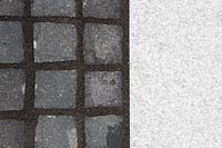 Making a mixed material patio - detail of paving where large porcelain slabs are mixed with granite setts