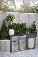 Outdoor kitchen with sink and freezer and small orange tree in a white planter plante r- The Retreat, RHS Malvern Spring Festival 2017 - 