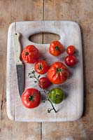 Different varieties of tomatoes on wooden chopping board