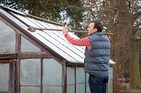 Brushing snow off a greenhouse roof