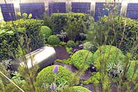 Urban roof garden with  stainless steel water container, drought tolerant plants, evergreen topiary and solar panels. 'Up on the roof', RHS Chelsea 2006.  