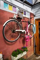 Bicycle mounted on wall painted  brown in a covered entertaining area, June.