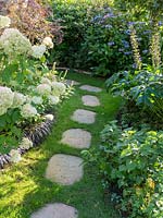 Clever use of a paving stone path through the lawn which separates the black and white bed from the blue.